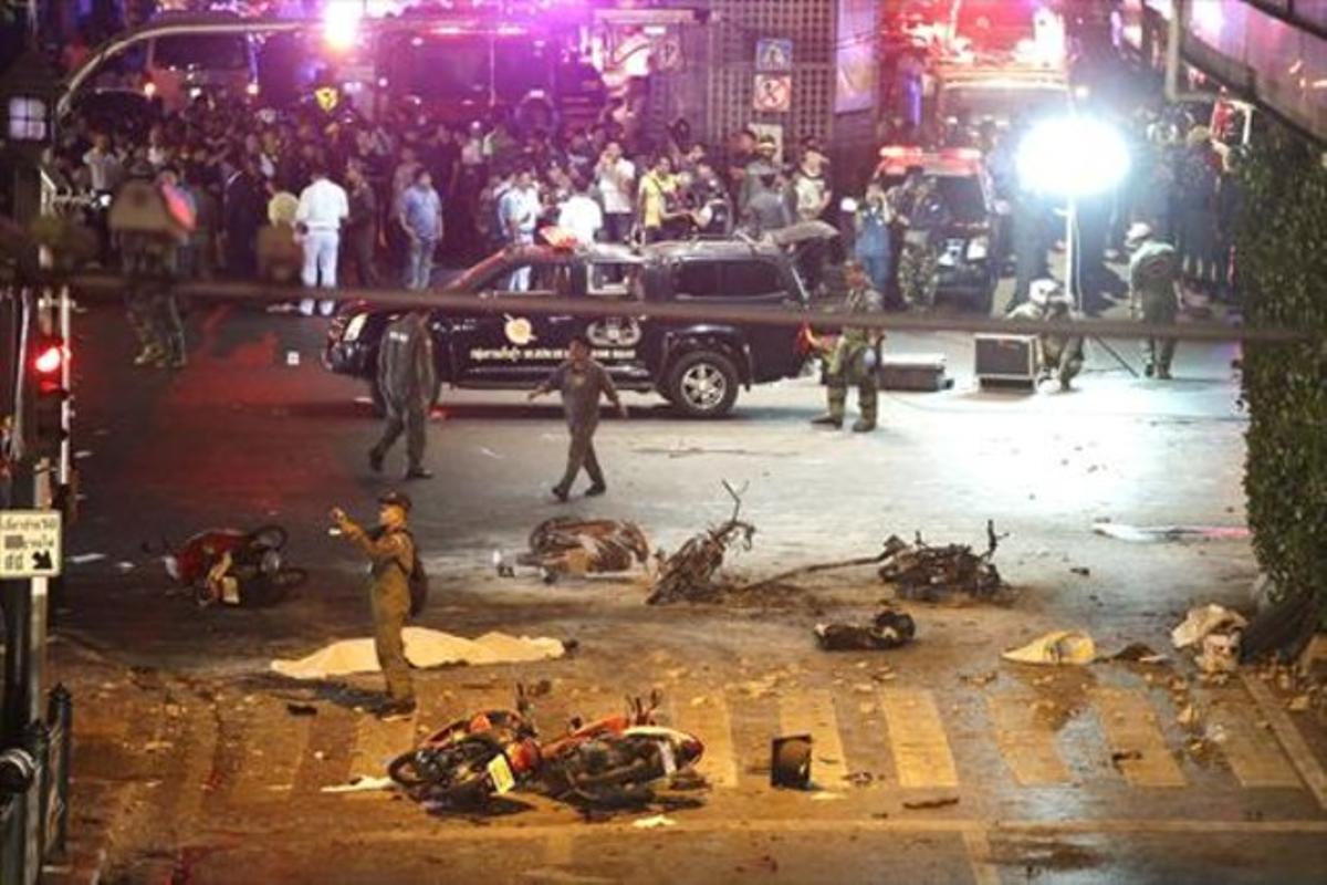 Un policia fa fotografiesdels desperfectes per la detonació a Bangkok.