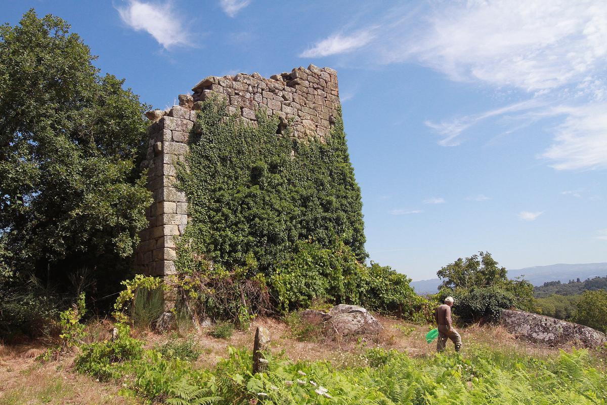 Un hombre pasea junto a la torre de Torán, en Taboadela, que la maleza invade. // IÑAKI OSORIO