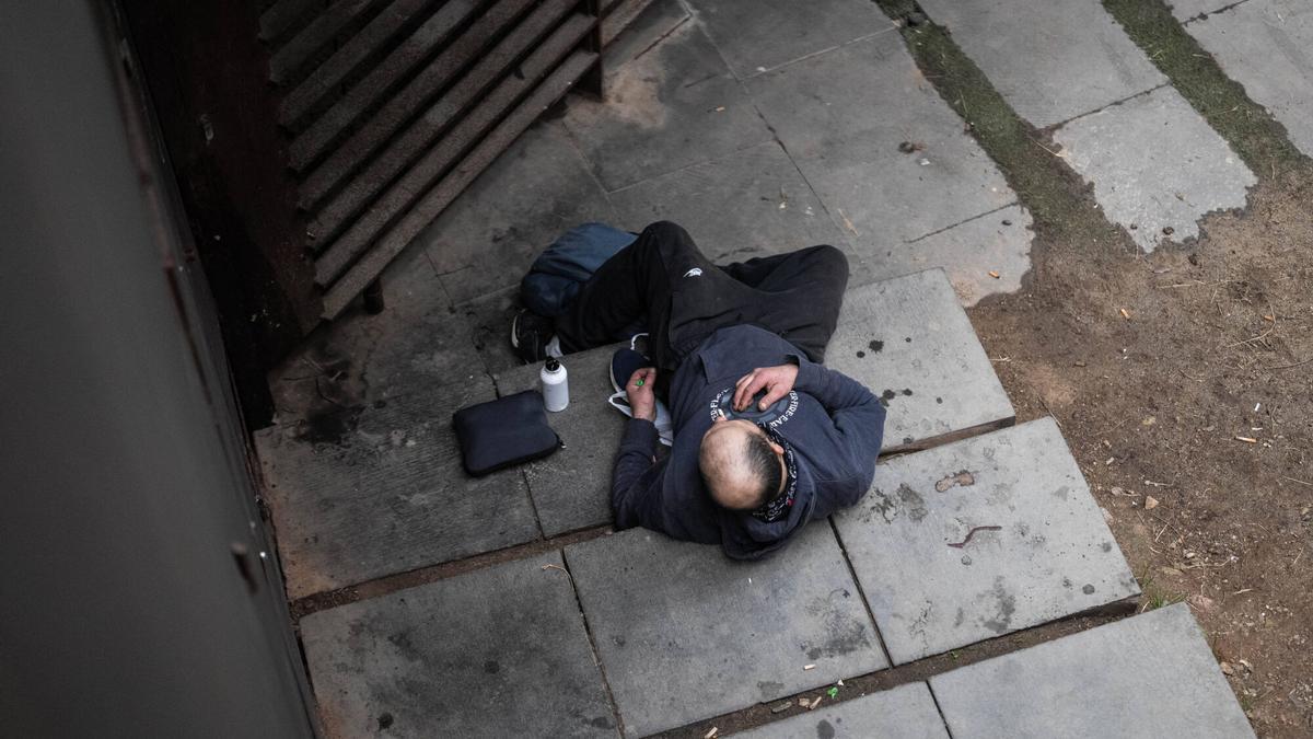 Un hombre tendido en los escalones que descienden a la necrópolis romana de la plaza Vila de Madrid, en el barrio Gòtic de Barcelona.