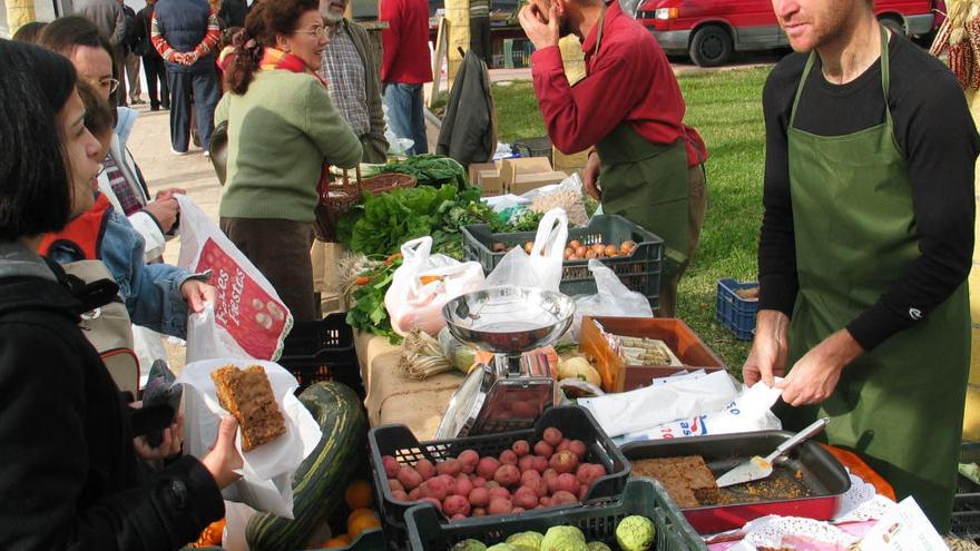 Varias personas deciden qué comprar en un puesto de fruta.