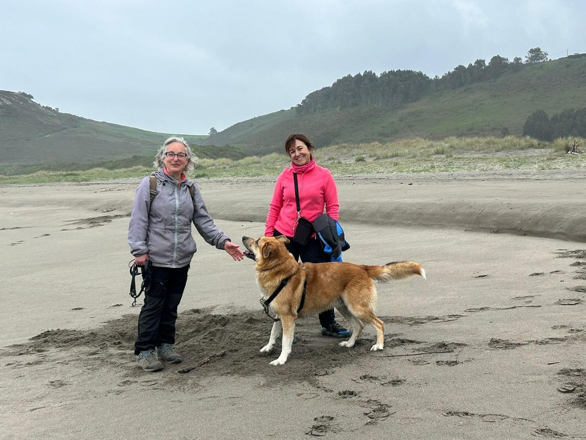 Marta Villamil y Belén García con su perro, Draco, en el playón de Bayas.