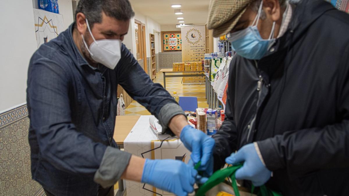 Mohamed reparte una bolsa de alimentos a un vecino en el Centre Cultural Islàmic de Sants.