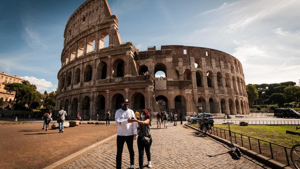 Dos personas con mascarilla junto al Coliseo en Roma