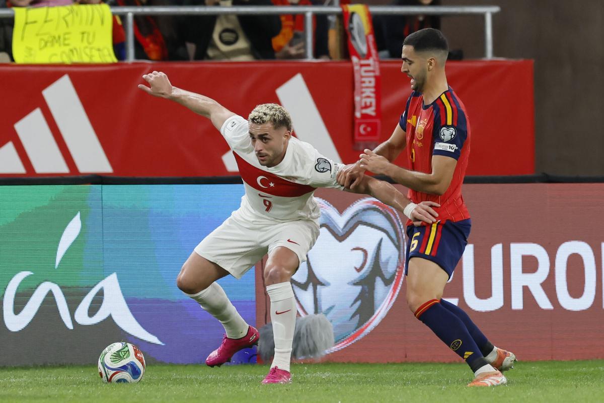 SEVILLA, 18/11/2025.- El centrocampista de Turquía, Baris Alper Yilmaz (i), protege el balón ante el centrocampista de la selección española, Mikel Merino, durante el encuentro correspondiente a la fase de clasificación para el Mundial 2026 que disputan hoy martes España y Turquía en el estadio de La Cartuja, en Sevilla. EFE / José Manuel Vidal.