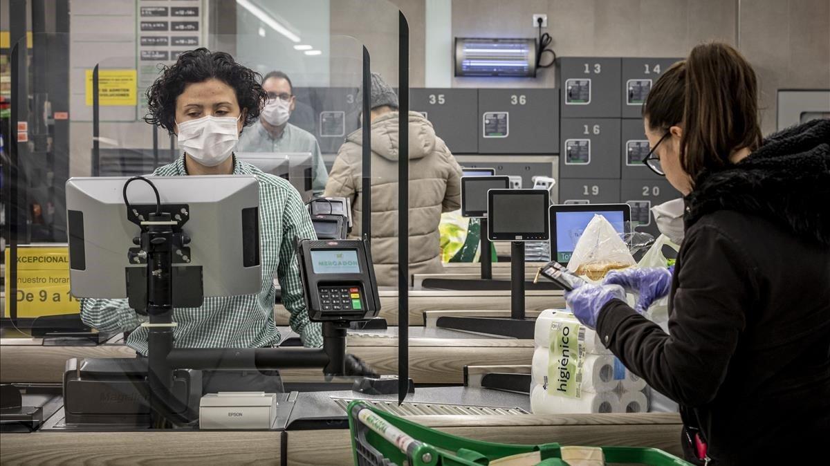 Después de unas primeras semanas en las que se vivieron escenas de caos en los supermercados, las empresas líderes de alimentación establecieron protocolos estrictos de seguridad tanto para sus trabajadores como para los clientes. Los departamentos de comunicación de dichas empresas se esforzaron en borrar las imágenes de descontrol que se habían visto. Mientras una quiosquera se intentaba proteger del posible contagio del virus con un simple plástico, la empresa Mercadona instaló, en tiempo récord, mamparas de metacrilato en las cajas de todos sus supermercados, como este de Valencia, en esta foto tomada el 24 de marzo. La lucha ante la pandemia era desigual 