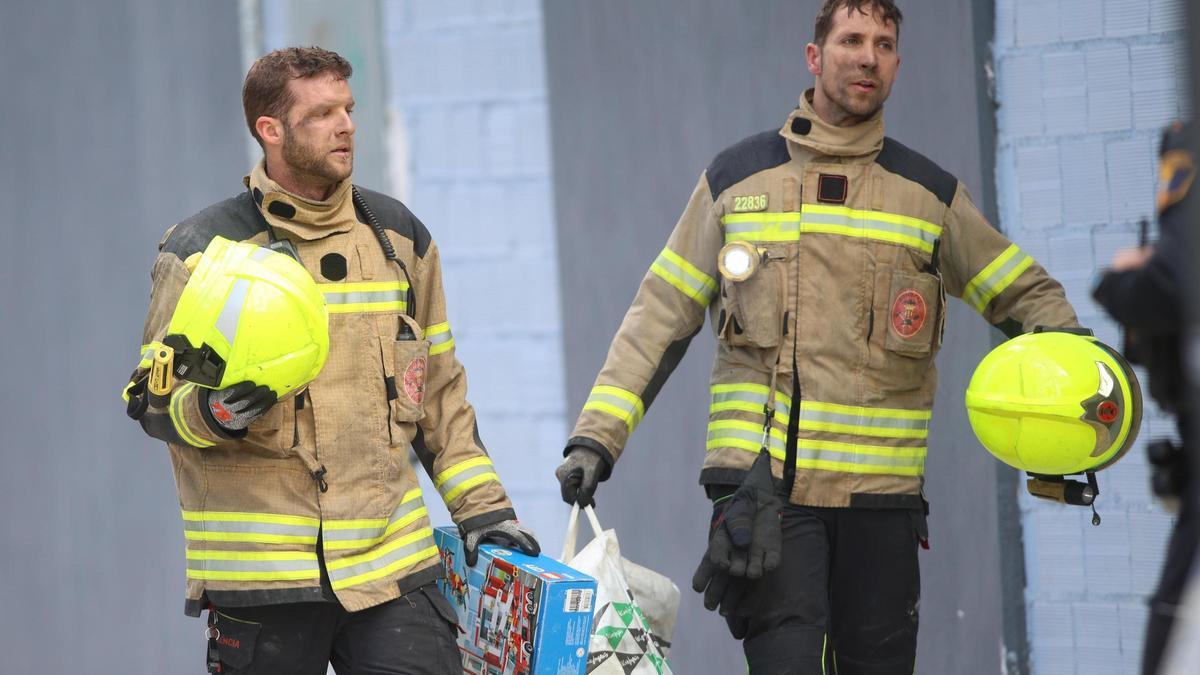 Dos bomberos rescatan enseres de una de las viviendas de Safranar menos afectadas por el fuego.