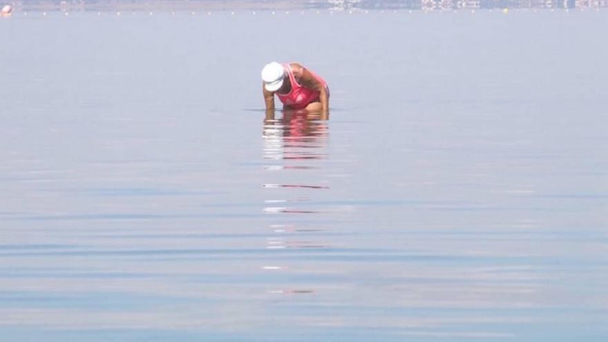 Una bañista recoge crustáceos del fondo marino.