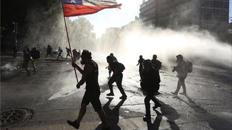 Miembros de carabineros dispersan a los manifestantes lanzando agua durante las protestas en contra del Gobierno.