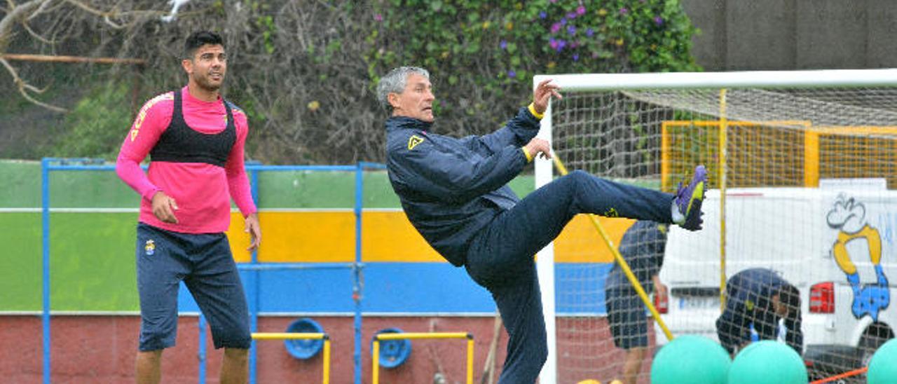 El entrenador de la UD Las Palmas, Quique Setién, controla un balón mientras Aythami Artiles está tras su espalda.