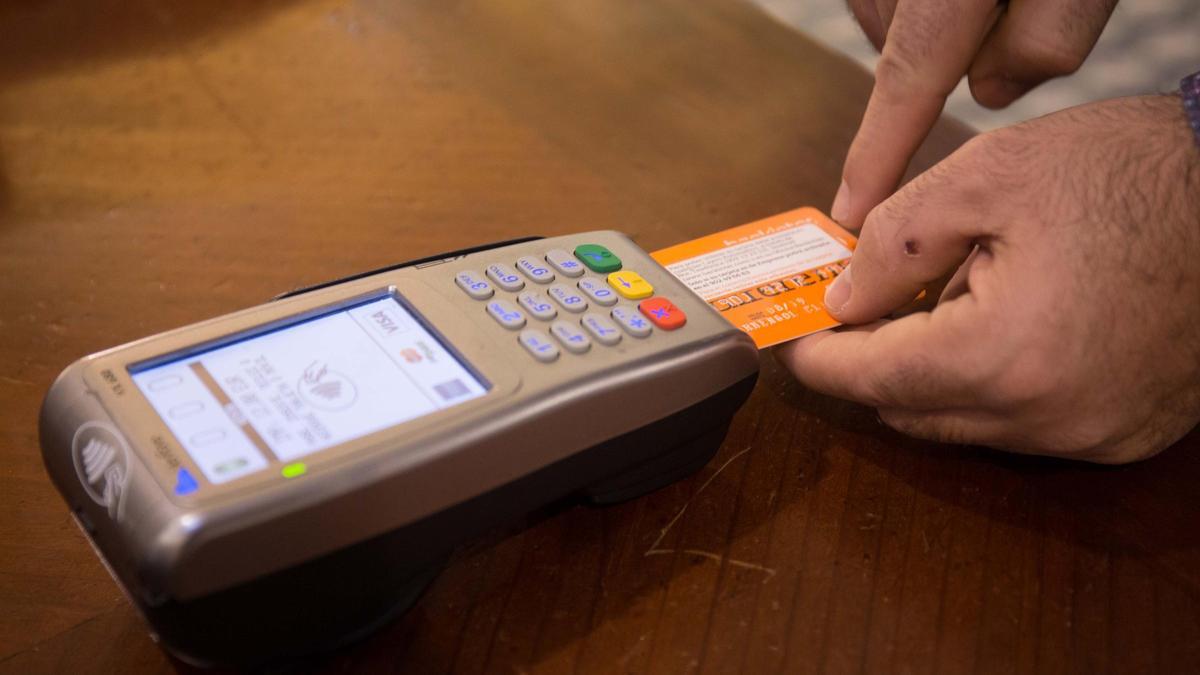 Un cliente introduce una tarjeta de crédito en un datáfono, en una foto de archivo.
