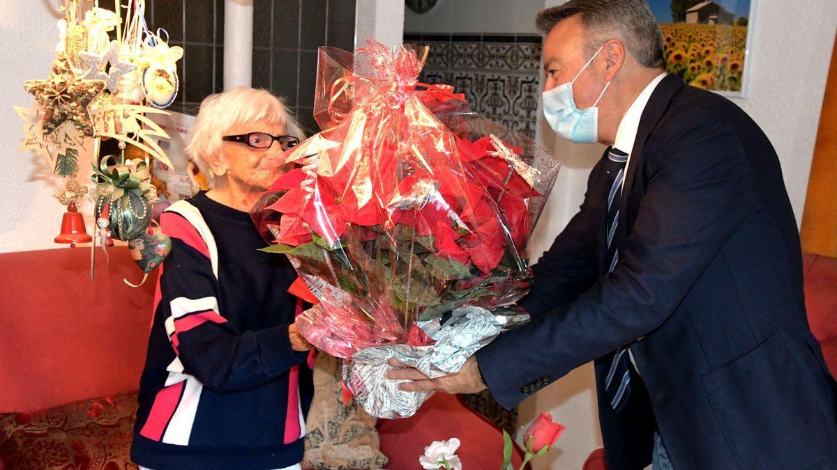 Rosa María recibe una flor de pascua de manos del alcalde.