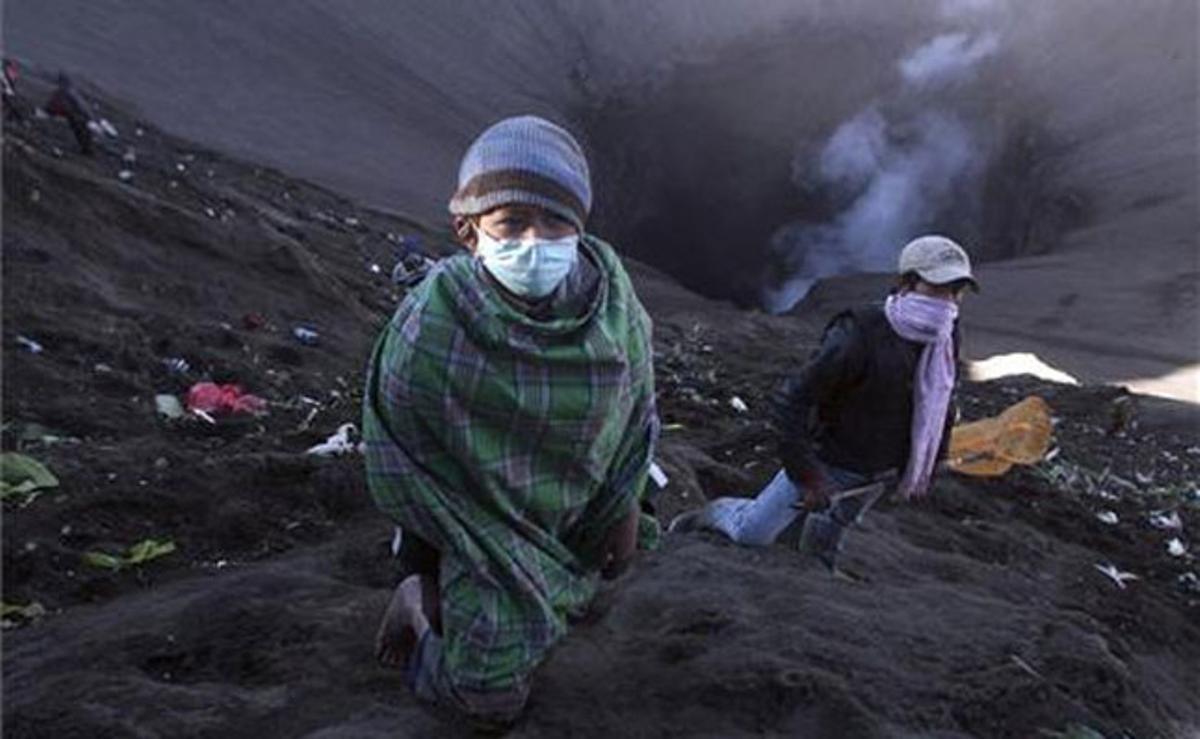Dos nens esperen al costat del cràter del mont Brom per recollir el menjar que tiren els pelegrins que van assistir a la celebració de la festivitat de Kasada, a Probolingo (Indonèsia).