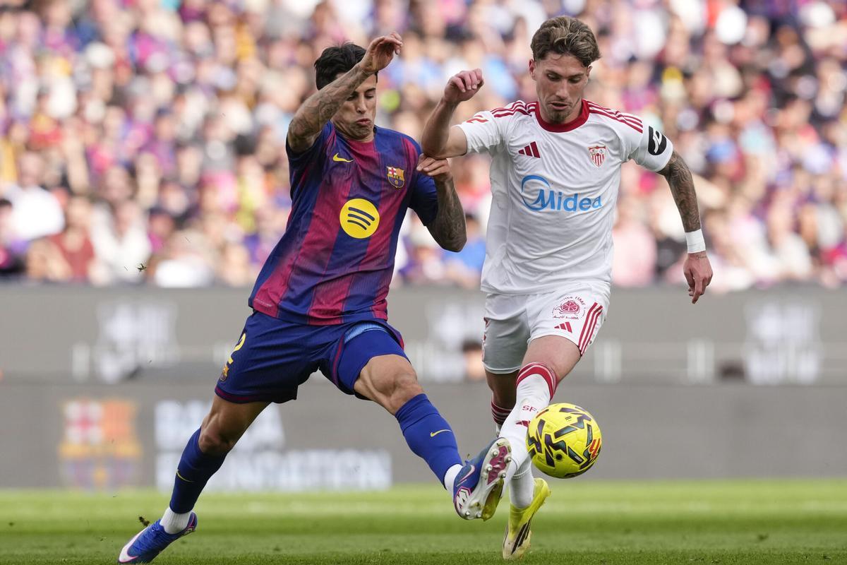 BARCELONA, 15/03/2026.- El defensa del FC Barcelona João Cancelo (i) pelea una posesión ante Carmona, del Sevilla, durante el partido de LaLiga entre el Barcelona y el Sevilla disputado en el Camp Nou en Barcelona, este domingo. EFE/ Enric Fontcuberta