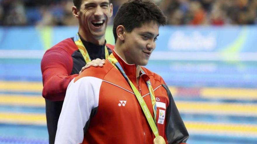 Phelps bromea con Schooling tras la entrega de medallas. A la izquierda, el nadador de Singapur posa con su ídolo cuando tenía ocho años. // Efe