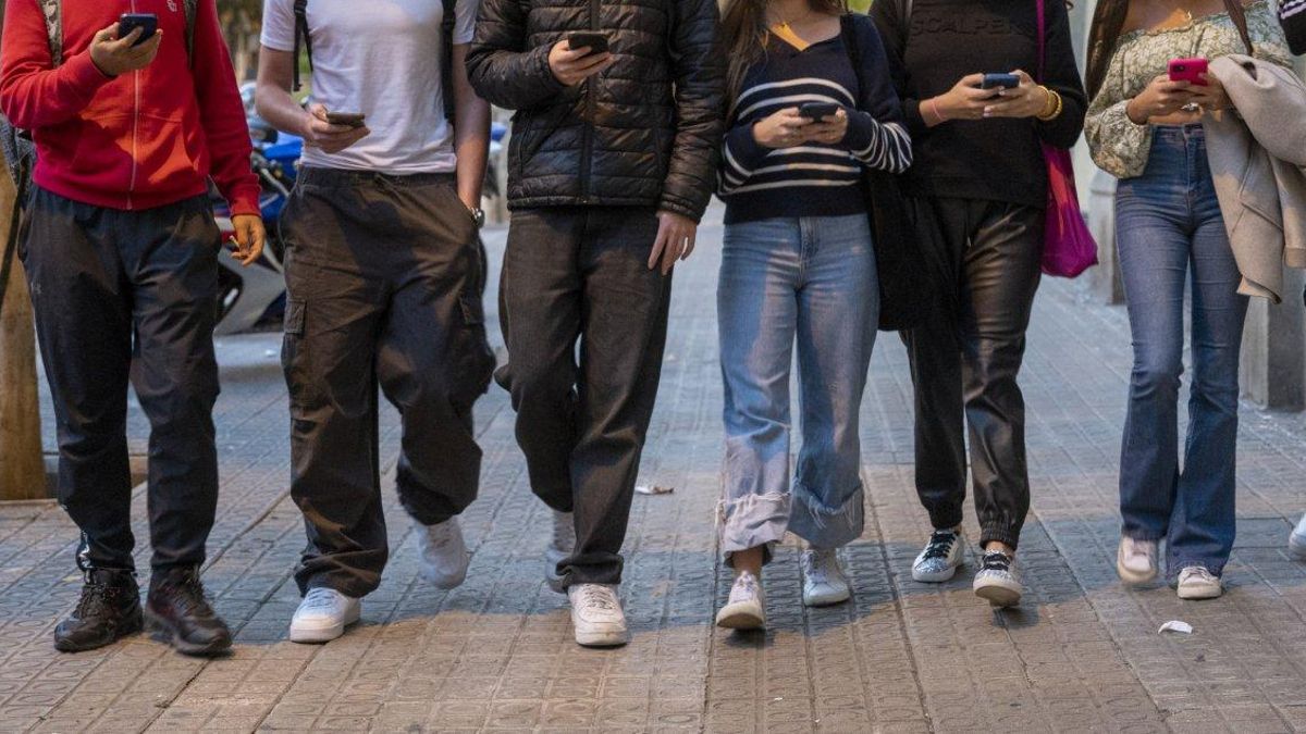 Un grupo de jóvenes consultando sus móviles en la calle, en Barcelona.
