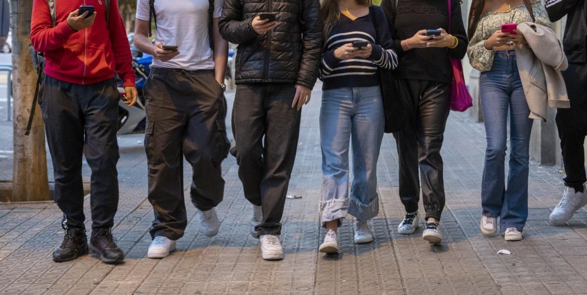 Un grupo de jóvenes consultando sus móviles en la calle, en Barcelona.