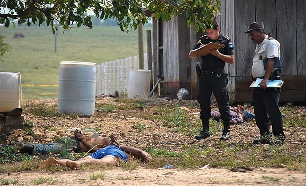 Uns homes de la Policia guatemalenca observen alguns dels cadàvers dels 26 homes i dues dones trobats aquest diumenge en una finca del municipi de La Libertad. Segons els primers indicis, haurien estat assassinats pel càrtel mexicà de Los Zetas.