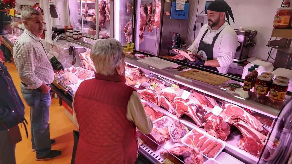 Varios clientes esperan su turno frente al mostrador de una carnicería.