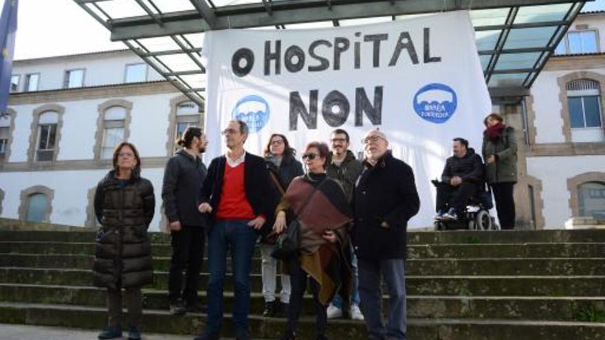 Miembros de Marea Pontevedra ante el cartel colgado del Hospital Provincial.