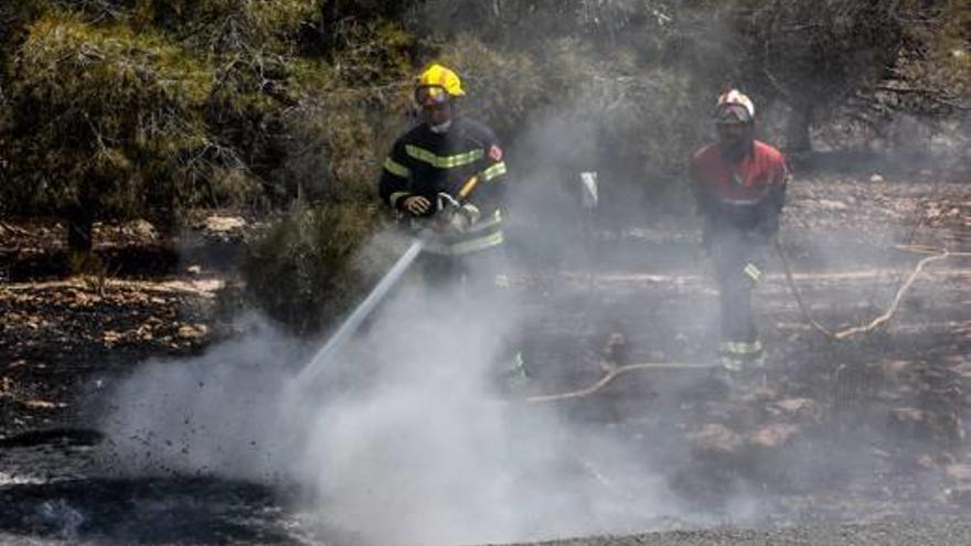 Los bomberos, durante las tareas de extinción del incendio, junto al camino del Faro.