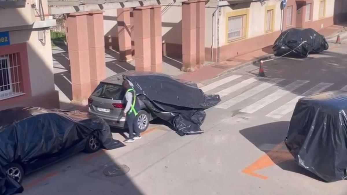 Un operario de la obra cubre con lonas de plástico un vehículo en Santa María de Gracia.