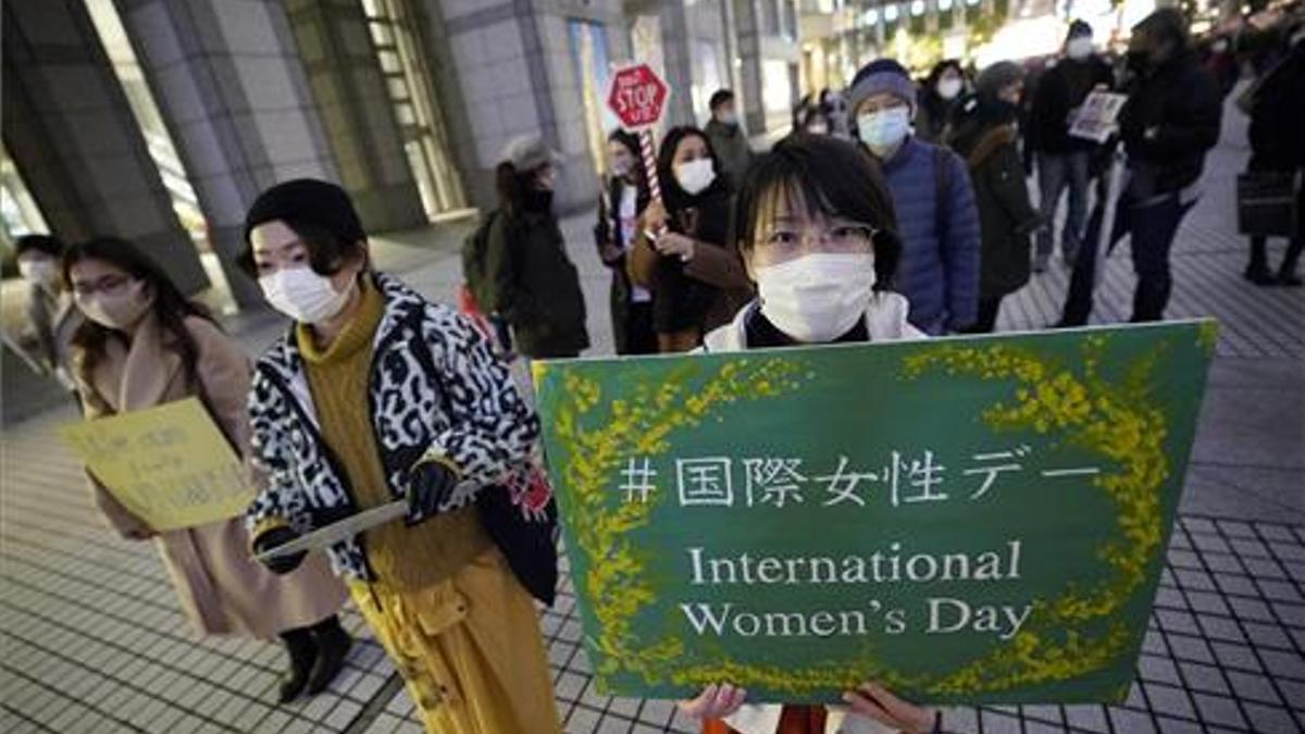 Una joven sostiene una pancarta mientras participa en una manifestación contra la violencia de género y la discriminación en Tokio.