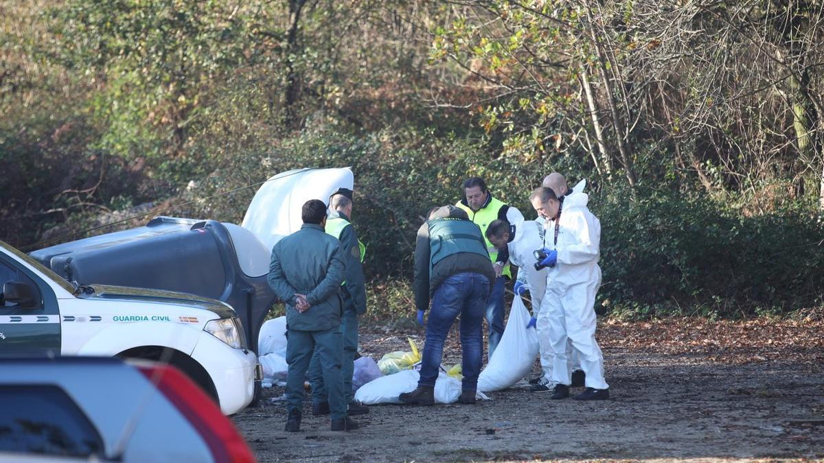Los investigadores inspeccionando el contenido del contenedor tras el que apareció el cadáver.