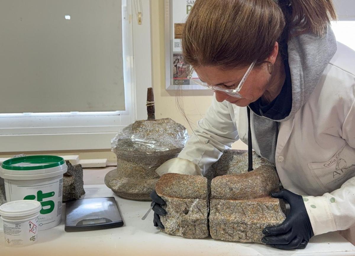 La restauradora Celia Casás, en su taller, con las piezas dañadas del cruceiro de Nigrán destrozado por un temporal.