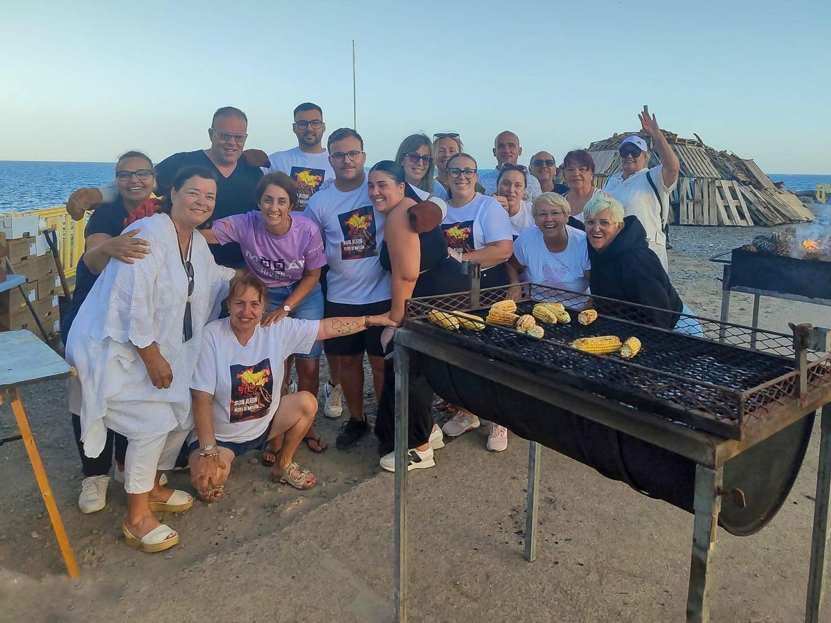 Alcaldesa y vecinos en la preparación de las piñas asadas.