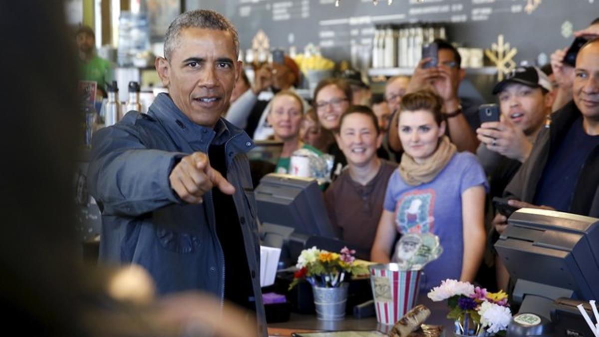 Obama asks members of the traveling press corps if they would like a pastry as he orders at Snow City Cafe in Anchorage