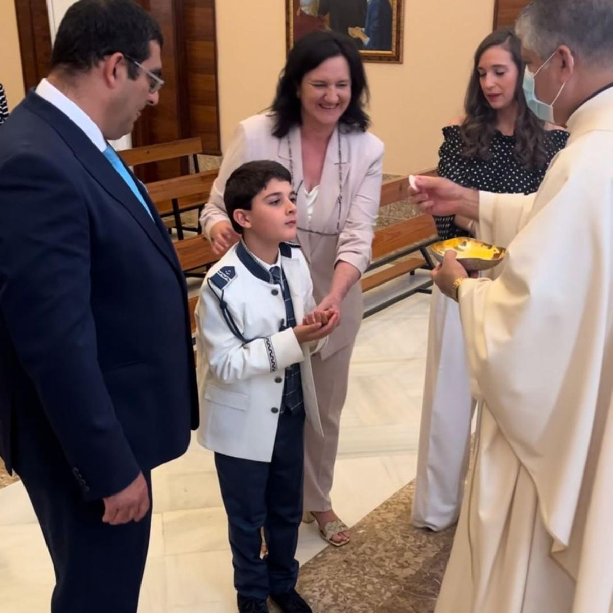 Rubén, en el momento que recibió la primera comunión, de manos del padre Imanol, y junto a sus padres, y la directora del CAIT de San Juan de Dios, Laura Casares.