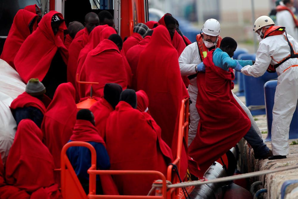 Migrants stand on a rescue boat upon arriving on ...