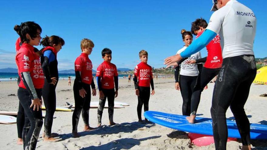 Un grupo de niños atiende a su monitor de la escuela Prado Surf, en Patos.