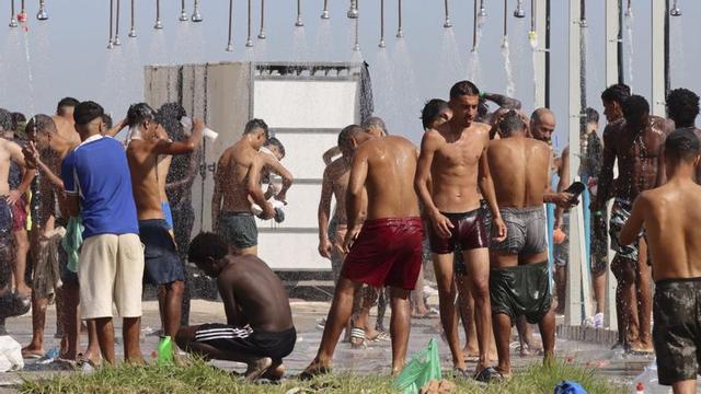 Un grup de persones migrants es dutxen a la platja d’El Trampolín de Ceuta, ahir. | REDUAN / EFE