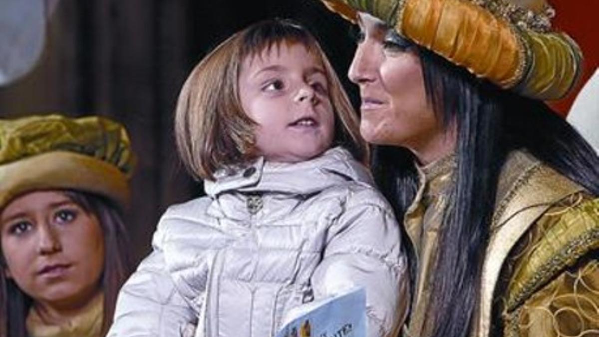 Una niña entrega la carta de los Reyes a la paje Estel en el Ayuntamiento de Barcelona.