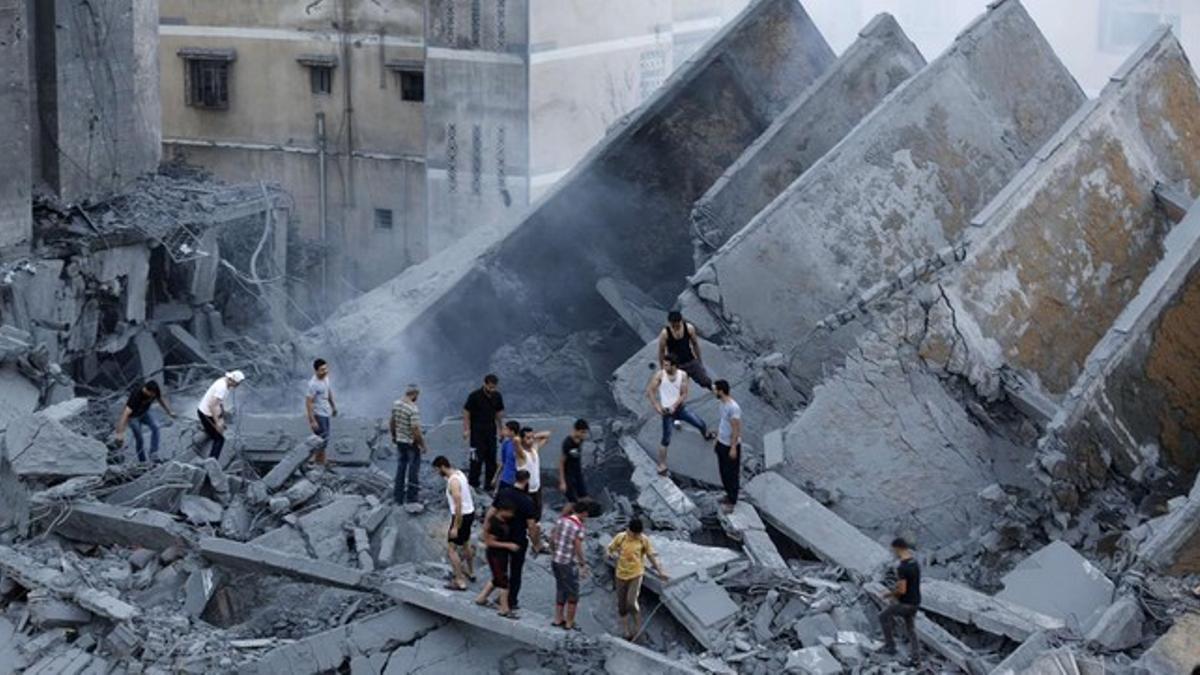 Palestinos inspeccionan los restos de Al-Basha, un edificio que fue destruido por un ataque aéreo israelí en Gaza