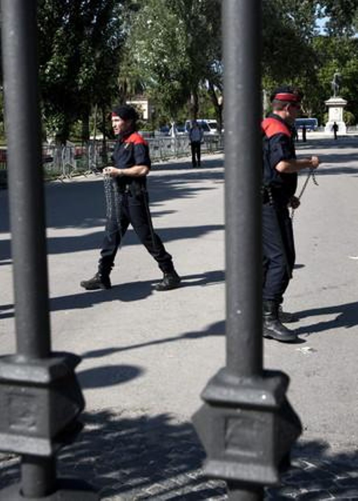 Dos mossos d’esquadra es dirigeixen a col·locar cadenes a les portes del parc de la Ciutadella.