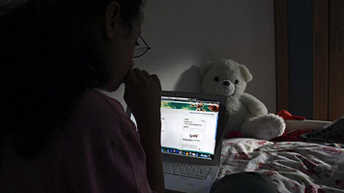 Una niña navega por internet, en su habitación.