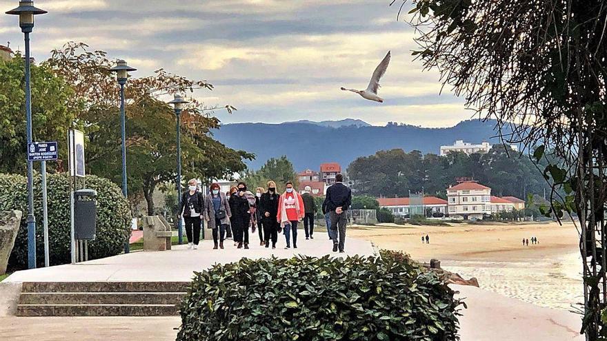 Grupos de personas paseando, ayer, por el frente marítimo de Cangas y la playa de Rodeira.