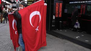 Un hombre vende banderas de Turquía frente a una oficina de cambio de moneda en Estambul.