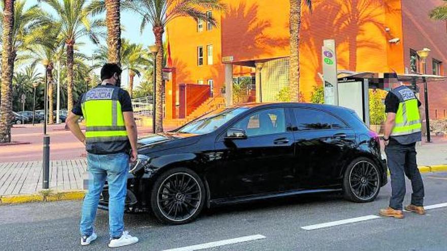 Dos policías en la puerta de la Comisaría de Elche con un turismo de alta gama recuperado. | INFORMACIÓN