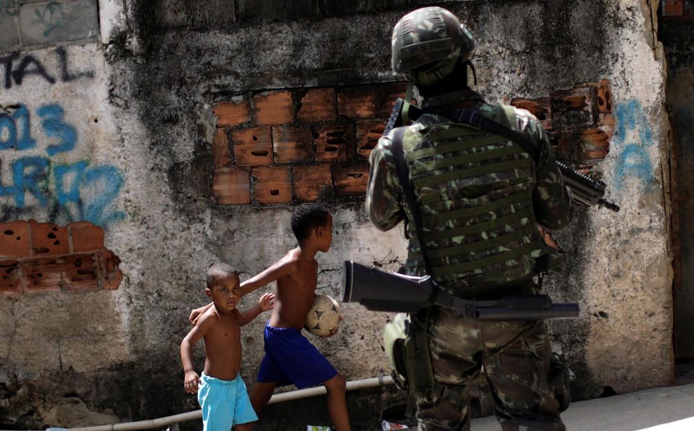 Unos niños observan como patrullan miembros de las fuerzas armadas durante una operación contra el narcotrafico en el barrio Lins de Río de Janeiro.