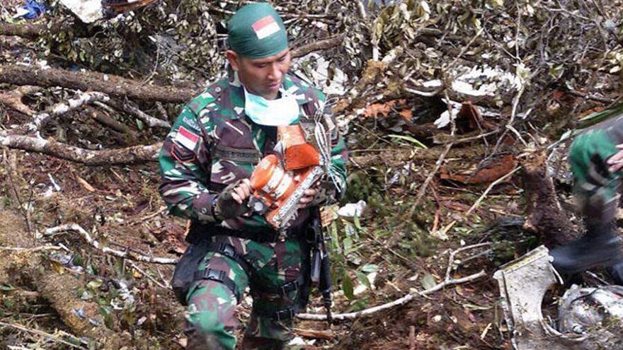 Un soldado traslada la caja negra del avión accidentado.