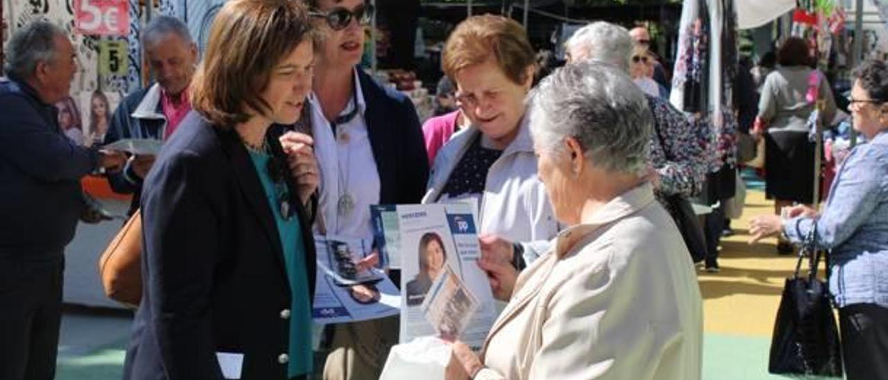 Pastor, con dos vecinas ayer por la mañana, explicando su programa en el mercado municipal.