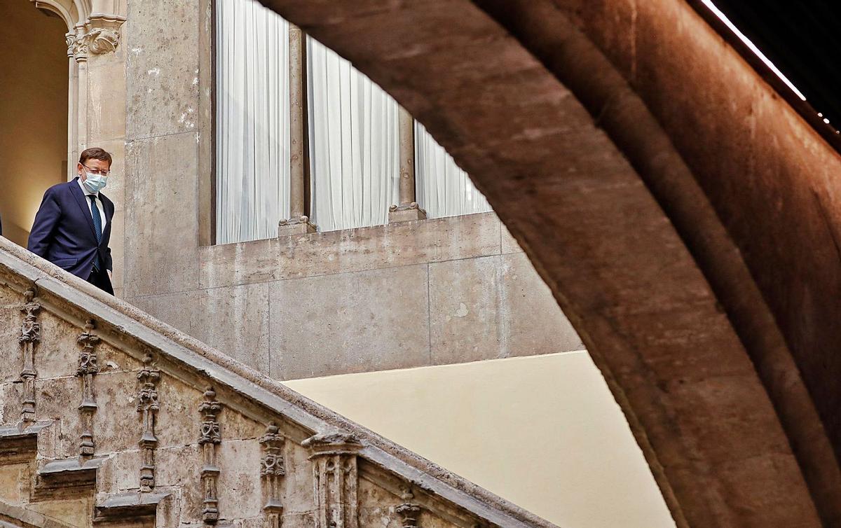 El presidente de la Generalitat Valenciana, Ximo Puig, baja por la escalera del patio gótico del Palau de la Generalitat.