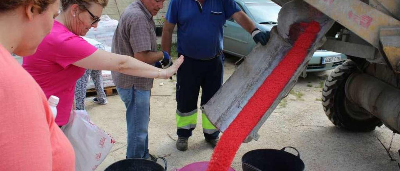 Los vecinos comprueban el color de la sal a su salida de la hormigonera en la que se realizó la mezcla, ayer, en el almacén municipal.