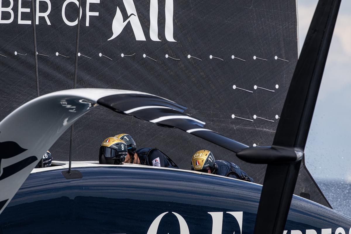 El AC75 del equipo francés Orient Express Racing Team, con los ciclistas en pleno trabajo en una de las regatas de la Louis Vuitton Cup.