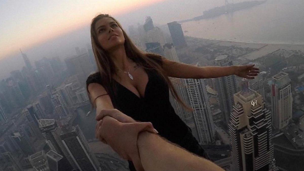 Viki Odintcova, de la mano de su asistente, sin arnés, a 300 metros de altura, a punto de hacerse un selfi de vértigo.