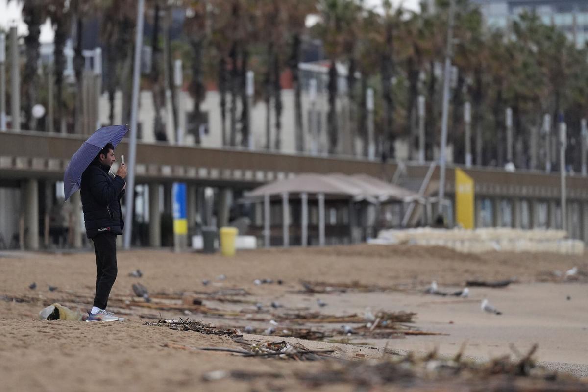 Vecinos de Barcelona pasean bajo la lluvia en la playa de la Barceloneta durante el temporal, a 19 de enero de 2026, en Barcelona, Cataluña (España).