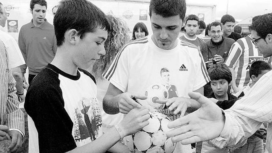 Villa firma un balón a un joven aficionado.